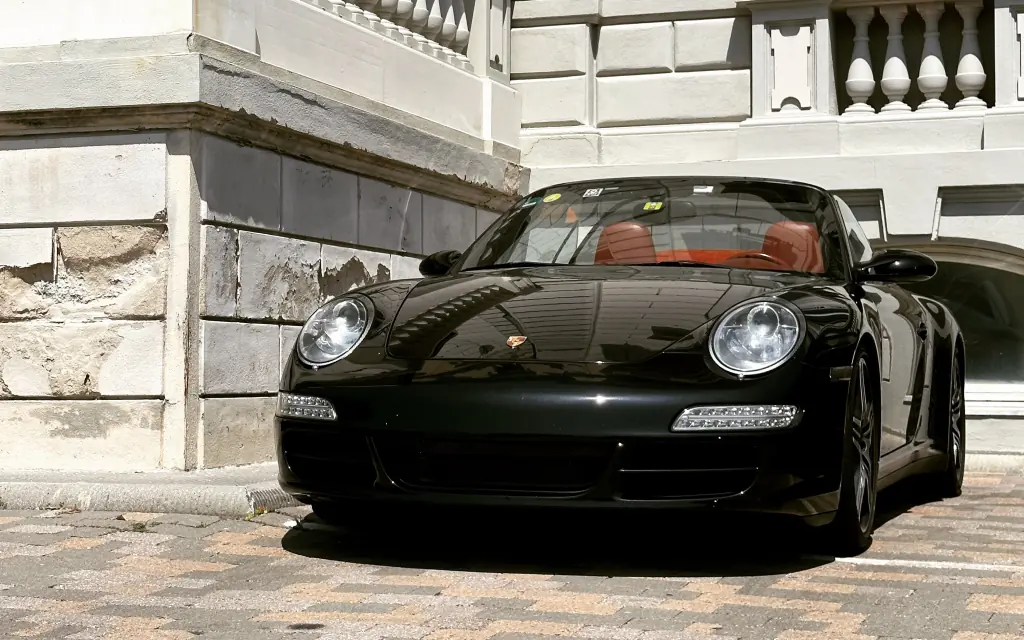 Een zwarte Porsche 911 opgesteld tegen het steen van een gebouw in Livorno